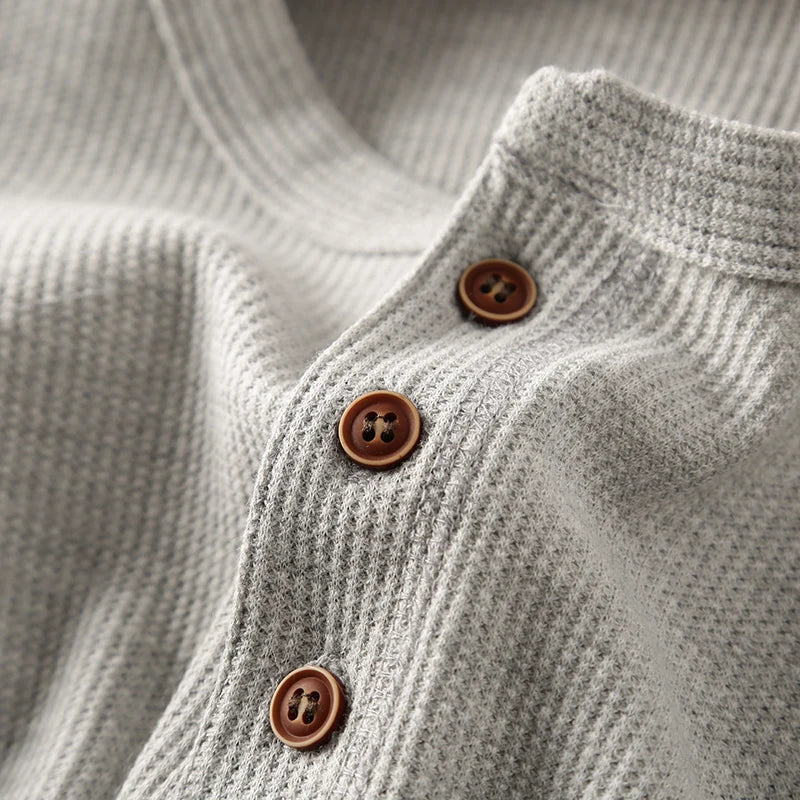 Close-up of the textured waffle knit fabric on a men's casual long sleeve shirt.