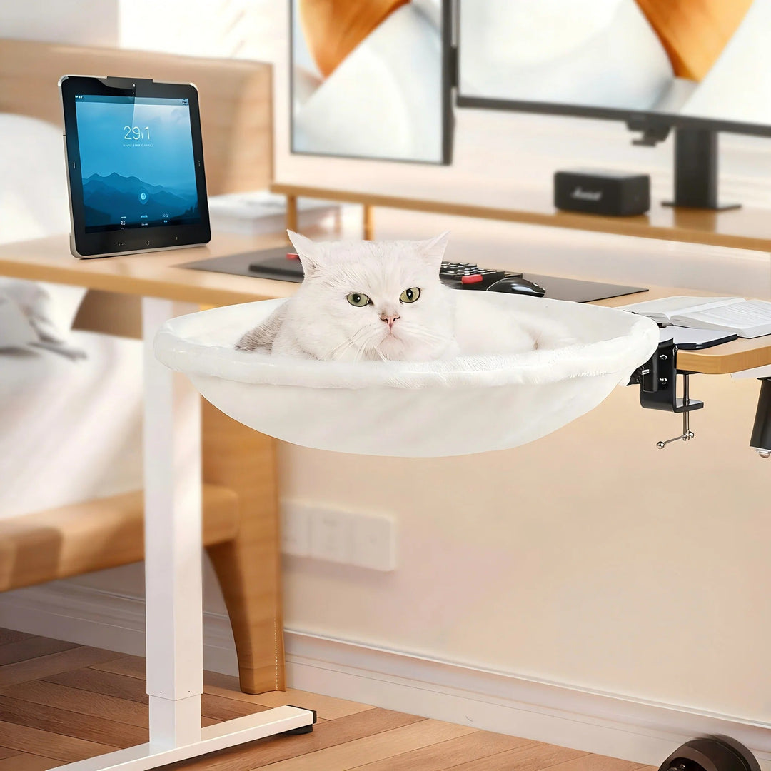 Cat looking out from a plush white faux fur desk bed, a comfortable and elevated pet perch.