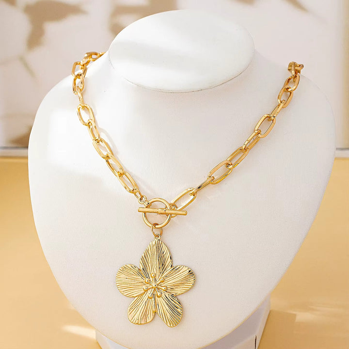 Textured gold-toned wisteria flower pendant necklace for women. Botanical floral charm with chunky chain & toggle closure.