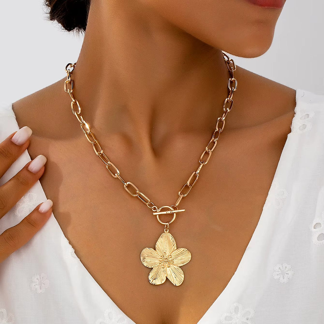 Women's gold-toned wisteria flower pendant necklace with textured floral statement charm on a chunky chain. Elegant.