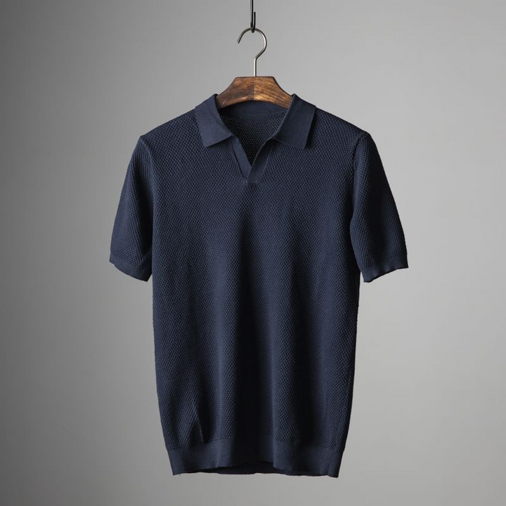 Close-up of men's textured short sleeve polo, highlighting geometric fabric detail & collared style.