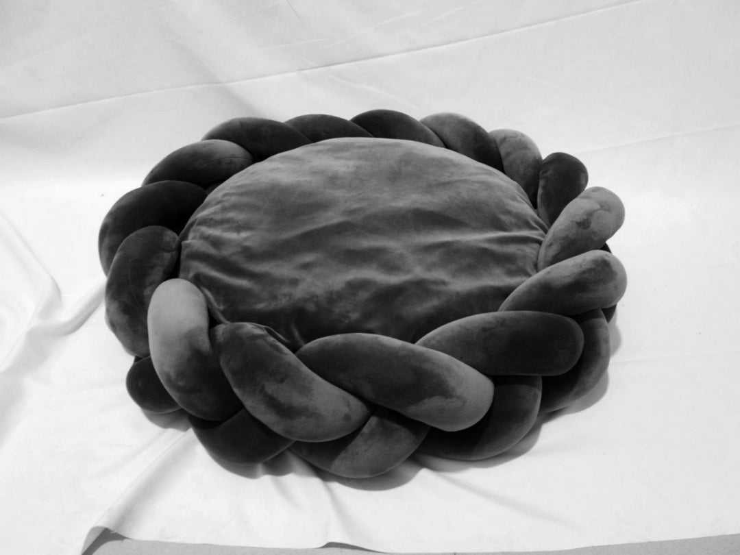 Perspective shot of a luxury plush dog bed, showcasing its fluffy interior and braided trim.