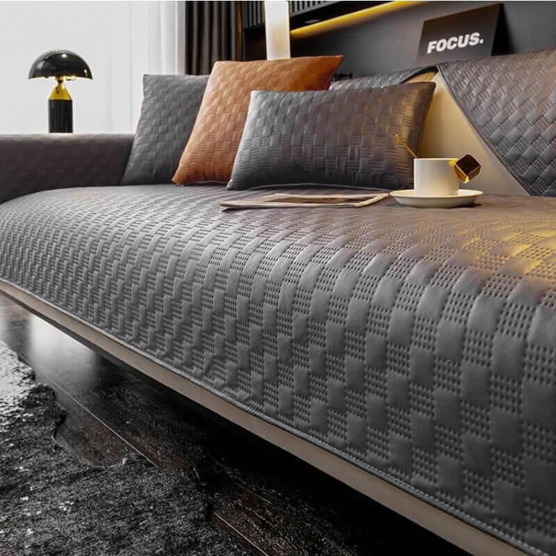 Water-resistant faux leather sofa cover in dark grey protecting a three-seater couch from spills and pet hair.