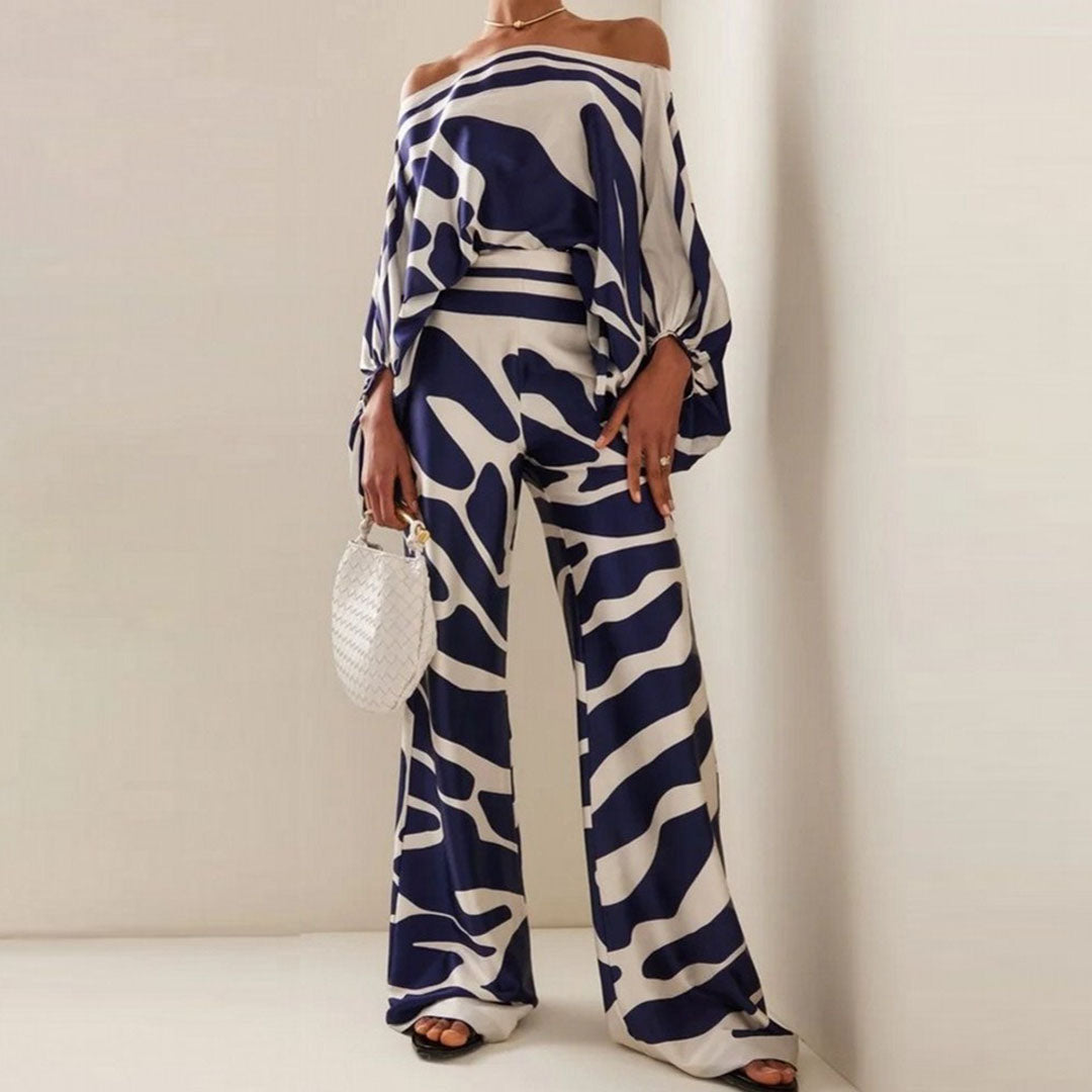 Modern women's two-piece one-shoulder set with trendy artistic print wide-leg pants. Perfect for resort style.