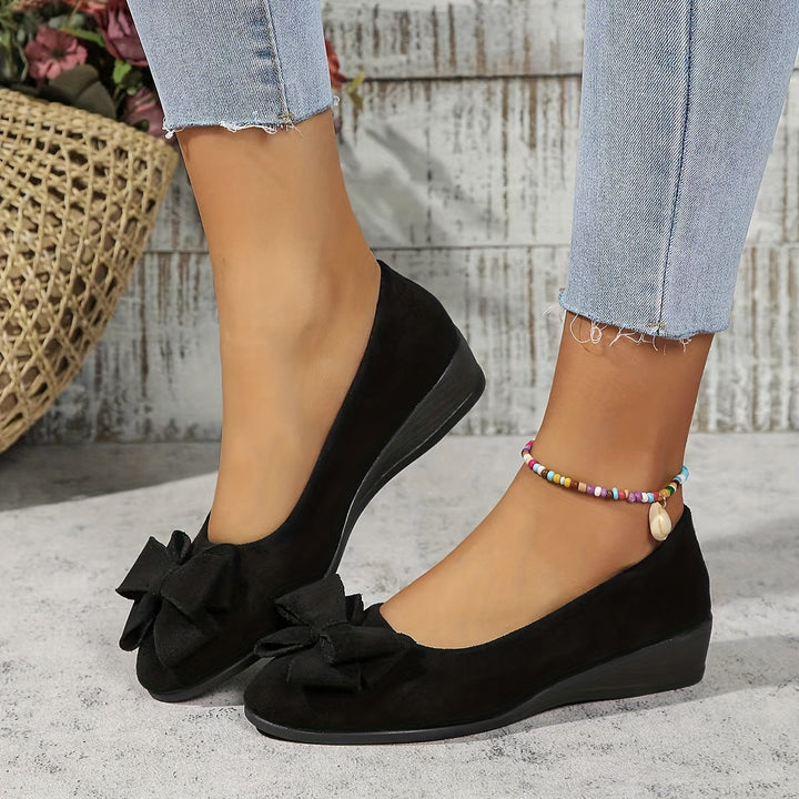 Elegant women's slip-on wedge heels with chic bow detail, perfect for dress or casual occasions.
