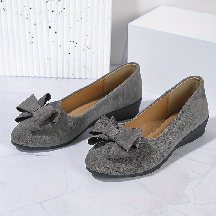 Stylish women's slip-on wedge heels featuring an elegant bow, comfortable everyday shoes.