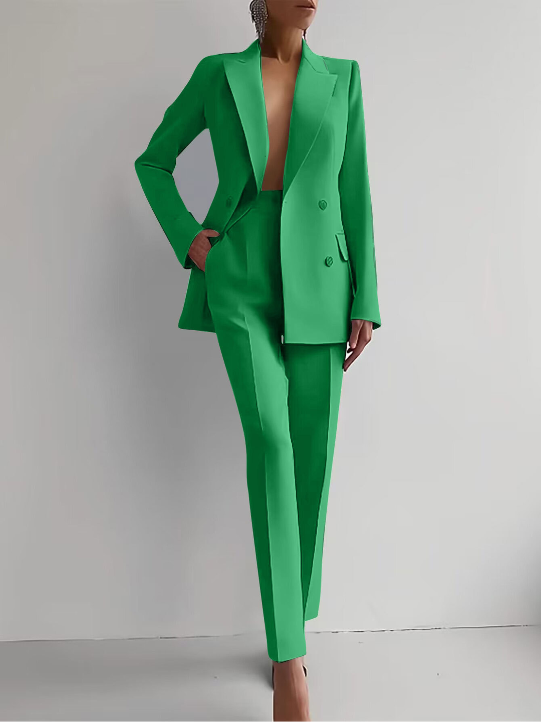 Full length view of a woman in a formal double-breasted suit with slim trousers, showcasing professional style.